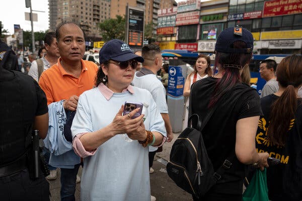 Winnie Greco, wearing a dark blue ball cap and holding a cellphone and a bottle of water, at a campaign rally for Eric Adams last month in Queens.